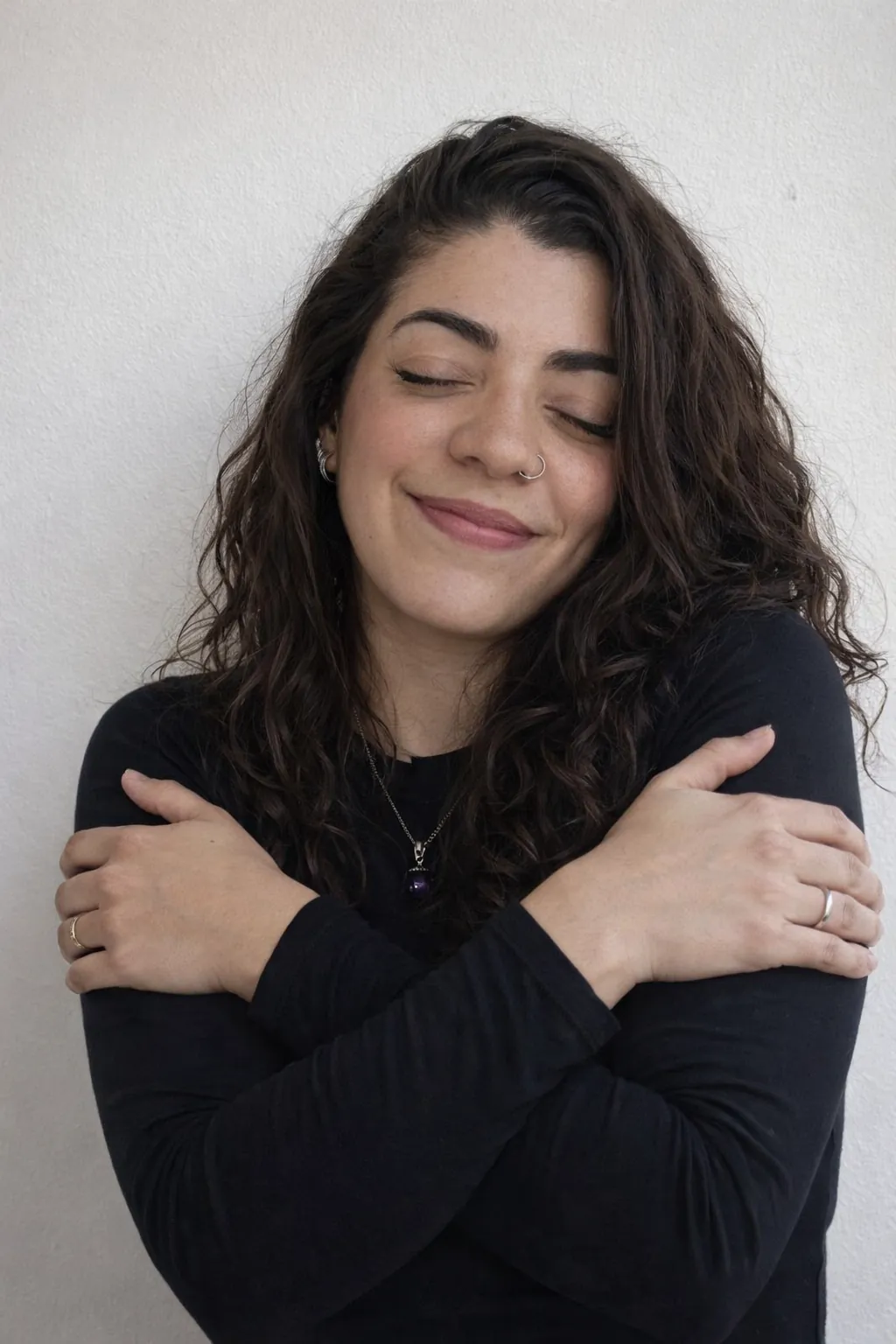 Kira Echenagucia abrazándose, sonriendo con los ojos cerrados